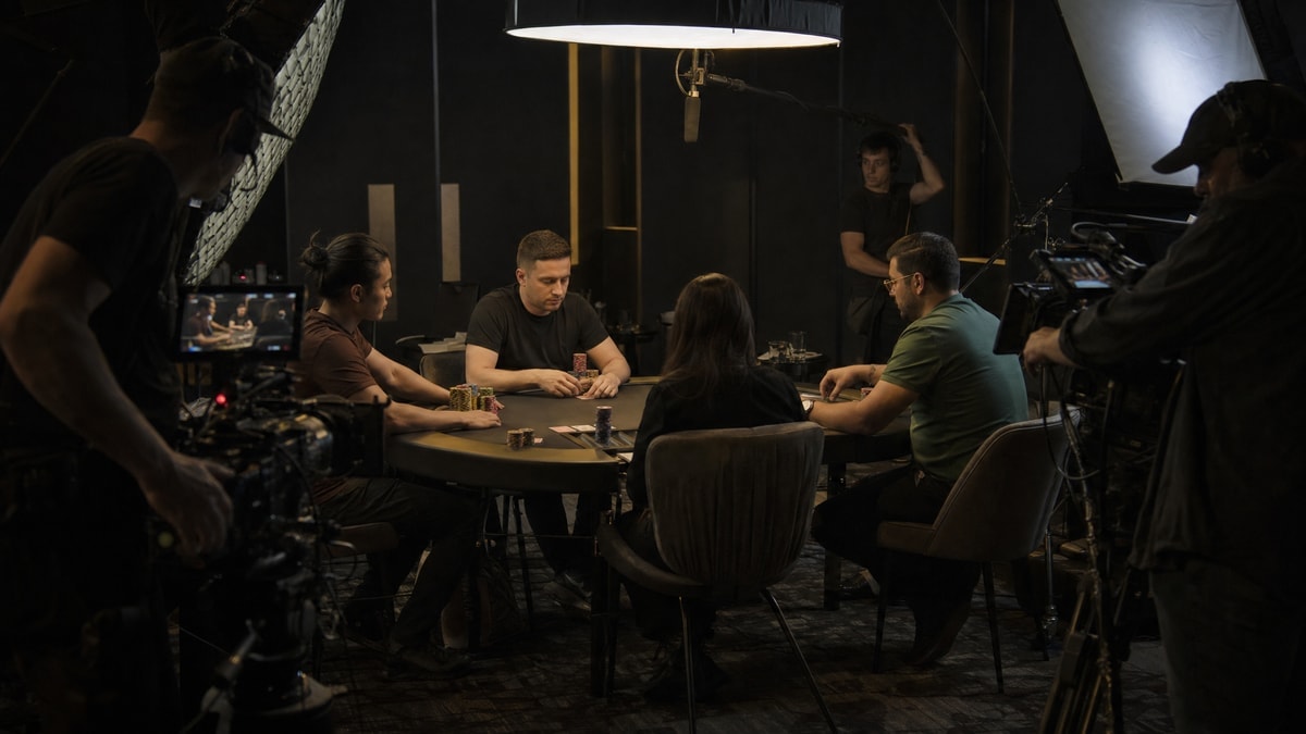 A film crew surrounds a poker table lit for a cinematic broadcast