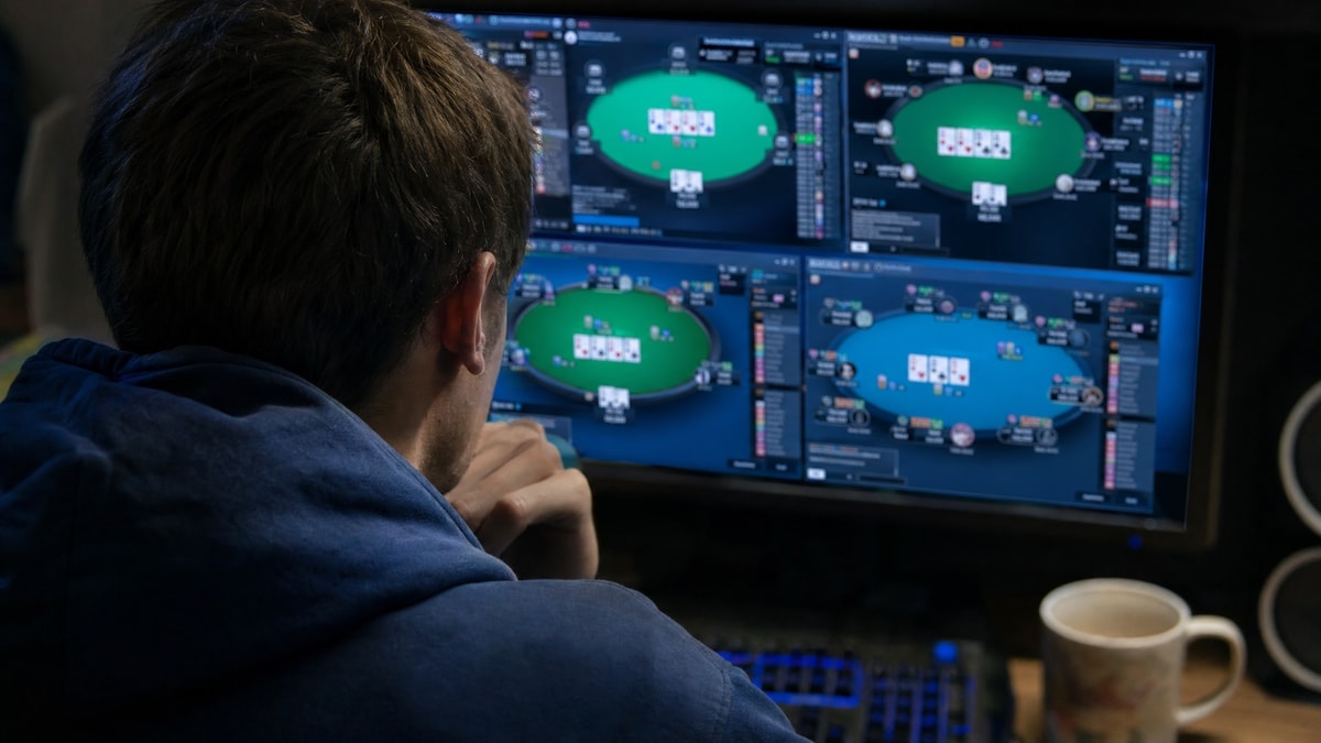 Online poker grinder studying a multi-table tournament on a laptop