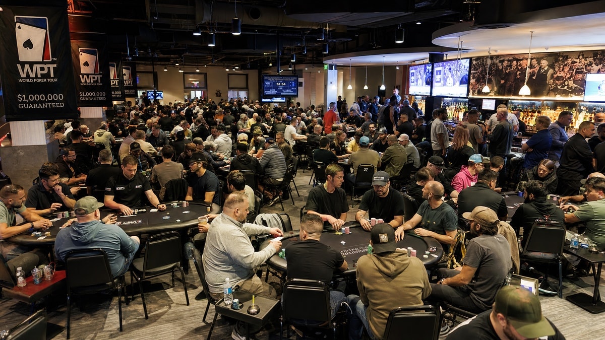 A busy live poker festival floor with a social lounge area for busted players